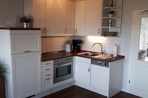 A modern kitchen with white cabinets, a stainless steel oven, a coffee maker, and a sink. - Holiday Dreams by the Sea 5.3 (Kühlungsborn East)