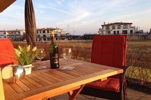 An outdoor table with a bottle of wine, glasses, and a potted plant. - Holiday Dreams by the Sea 5.3 (Kühlungsborn East)