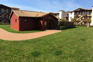 A red building with a tiled roof, a paved driveway, and a well-maintained lawn. - Holiday Dreams by the Sea 5.3 (Kühlungsborn East)