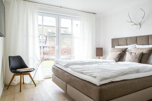 A bedroom with a bed, a chair, a window, and a wall-mounted deer skull decoration. - Holiday apartment with 2 bedrooms (Zingst)