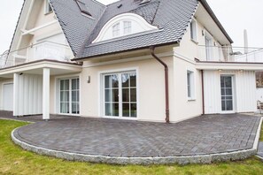 A two-story house with a curved roof, large glass windows, and a paved driveway. - Holiday apartment with 2 bedrooms (Zingst)