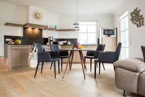 A modern kitchen with a dining area, wooden cabinets, and a TV. - Holiday apartment with 2 bedrooms (Zingst)