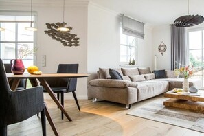 A modern living room with a sectional sofa, a dining table with chairs, and a coffee table. - Holiday apartment with 2 bedrooms (Zingst)