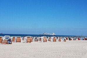 A beach with rows of beach chairs and a cruise ship in the distance. - Residence Am Kurpark (Warnemünde)