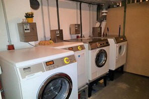 A row of Miele professional washing machines in a commercial setting. - Residence Am Kurpark (Warnemünde)