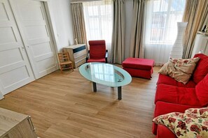 Ein Wohnzimmer mit Glastisch, rotem Sofa und Holzböden.