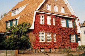 Ein traditionelles Gebäude mit einem steilen Satteldach, zahlreichen Fenstern und einer Backsteinfassade.