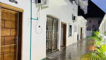A hotel corridor with a reception area, a wooden door, and a metal gate.