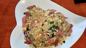 Un plato blanco con un salteado de verduras y carne, sobre una mesa de madera.