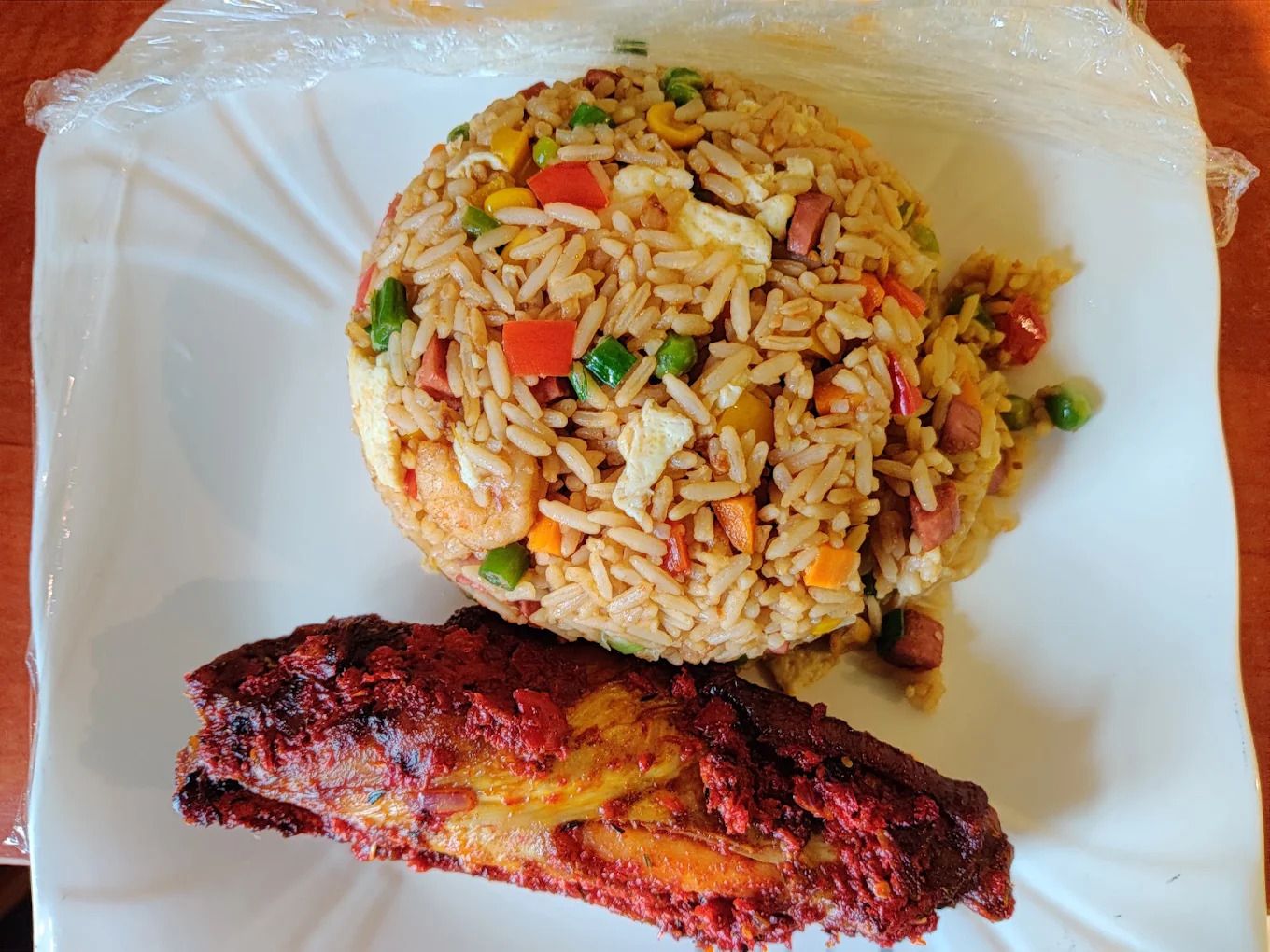 Un plato de arroz frito con verduras y un trozo de carne a la parrilla.