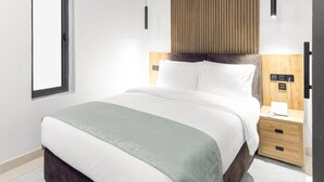 Une chambre d’hôtel avec un lit, une table de chevet et une fenêtre.