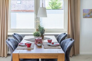 A dining table with placemats, a potted plant, and a lamp. - Holiday apartment Luzie (Büsum)