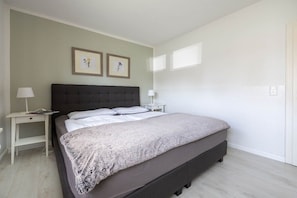 A bedroom with a bed, bedside tables, and two framed pictures on the wall. - Holiday apartment Luzie (Büsum)