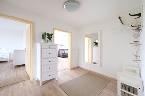 A room with a white dresser, a mirror, a hanging rack with items, and a view into another room. - Holiday apartment in Rade with barbecue (Rade)
