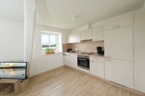 A modern kitchen with white cabinets, a built-in oven, and a window with a view of a body of water. - Holiday apartment in Rade with barbecue (Rade)