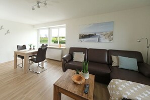 A modern living room with a wooden dining table, a brown leather sofa, and a coffee table with a remote control. - Holiday apartment in Rade with barbecue (Rade)