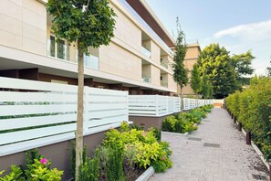 Ein Hotelgang mit Fliesenboden, weißen Geländern und verschiedenen Pflanzen und Blumen.