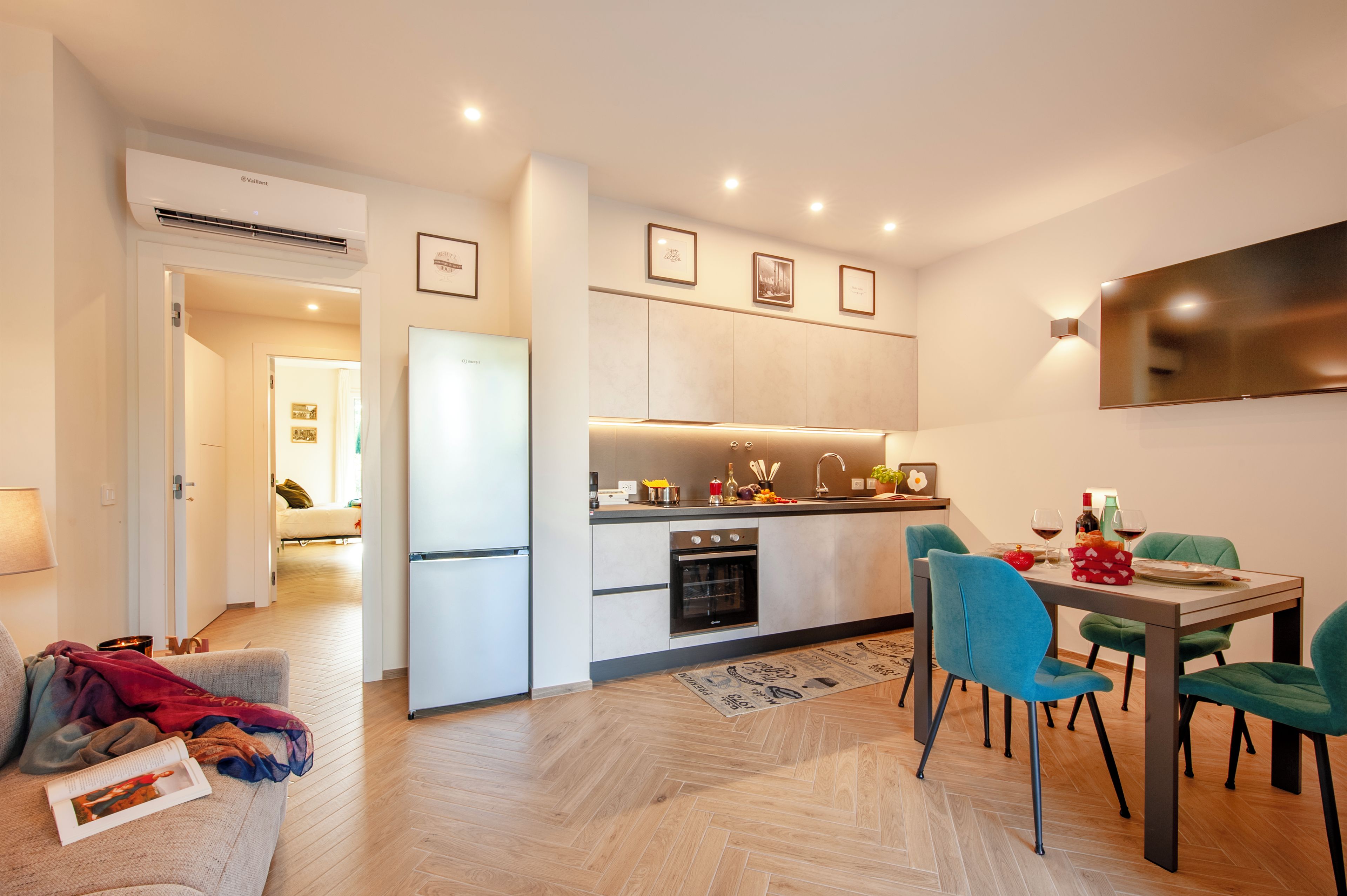 A modern kitchen with a dining area, a refrigerator, and a dining table with chairs.