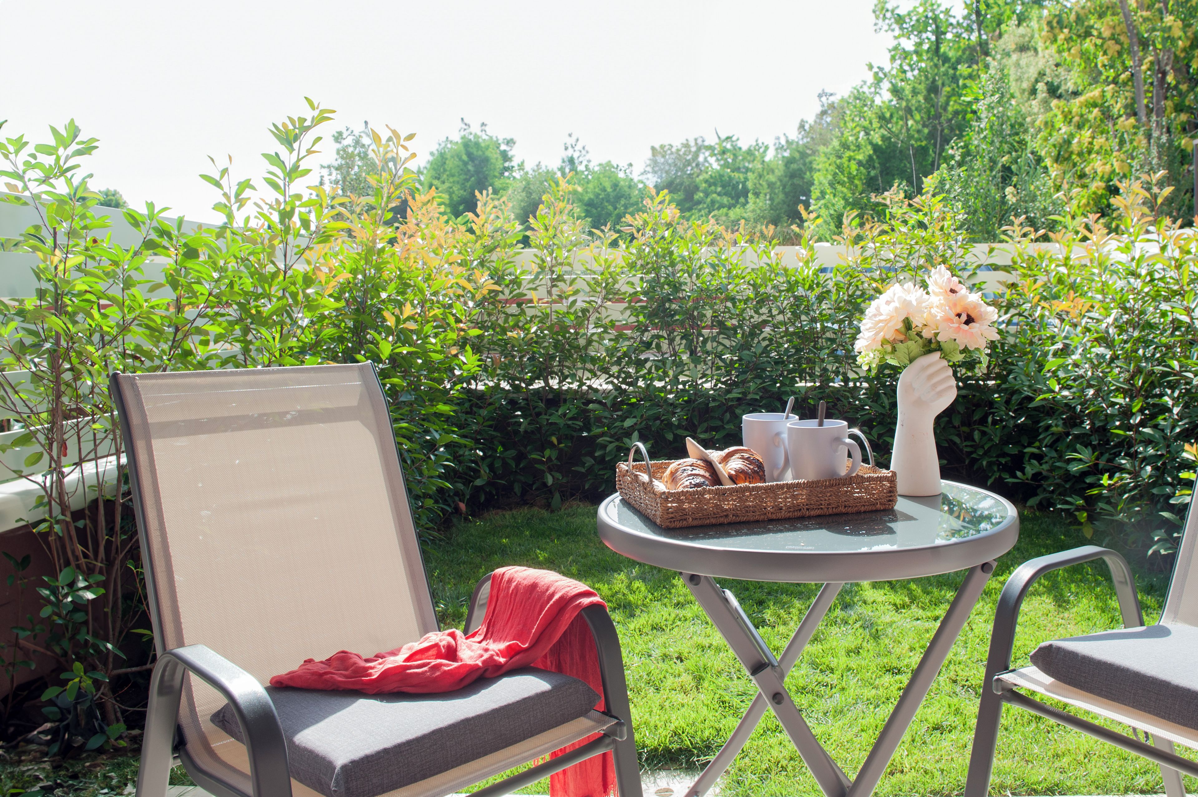An outdoor seating area with a table, chairs, and a basket of pastries.