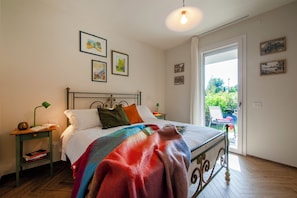 Ein Schlafzimmer mit einem Bett, Nachttischen, einem Fenster und Kunstwerken an den Wänden.
