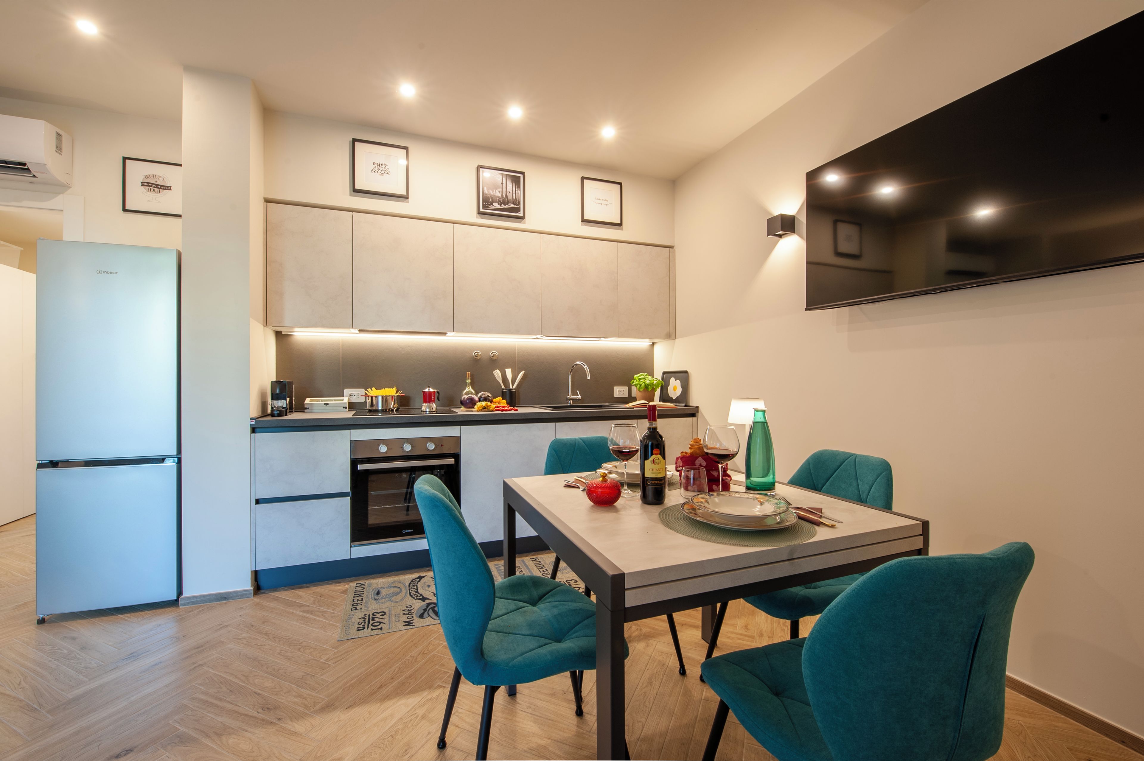 A modern kitchen with a dining area, featuring a built-in oven, a coffee machine, and a dining table with chairs.