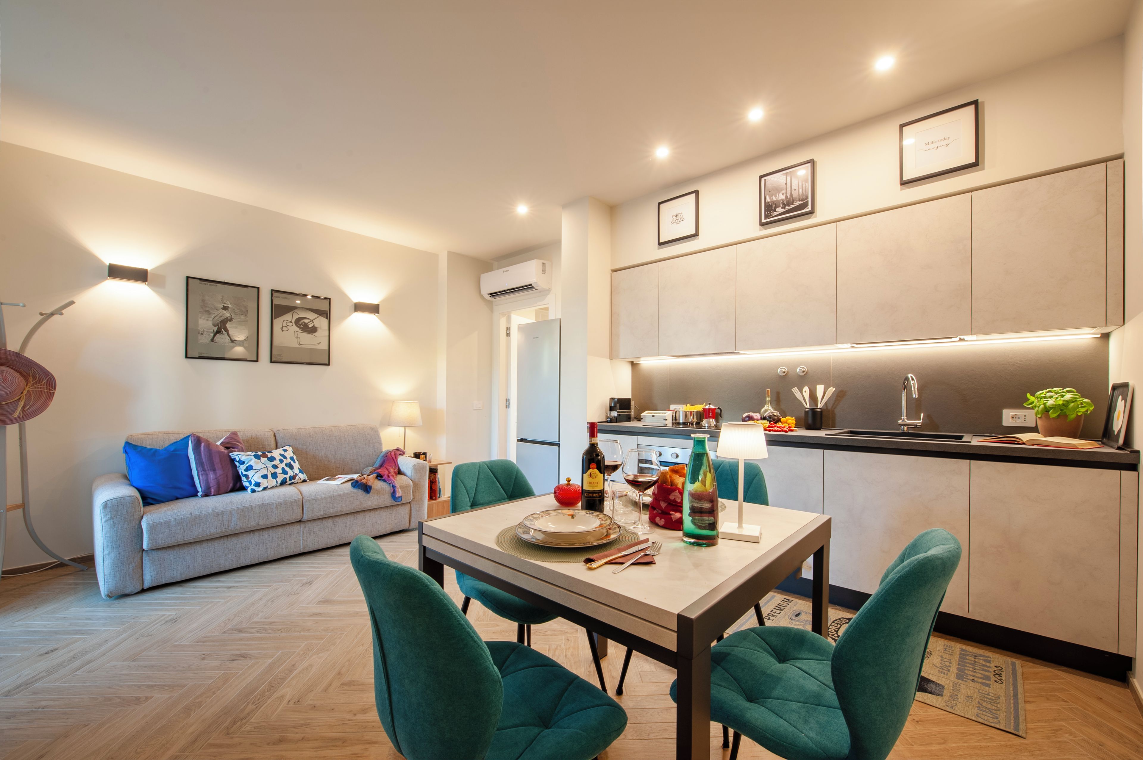 A modern living room with a sofa, a dining table with chairs, and a kitchen area with cabinets and a countertop.