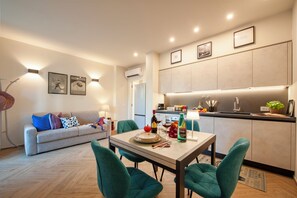 Una sala de estar moderna con un sofá, una mesa de comedor con sillas y una zona de cocina con armarios y encimera.