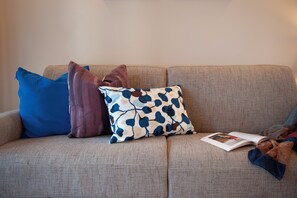 Ein Sofa mit mehreren Kissen in verschiedenen Farben und einer darauf liegenden Zeitschrift.