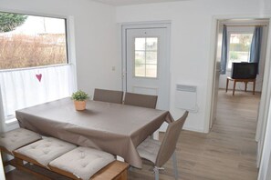 Et værelse med et bord, bænke, en dør, et vindue og et fjernsyn.
