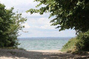 A beach with a clear view of the sea and distant land.