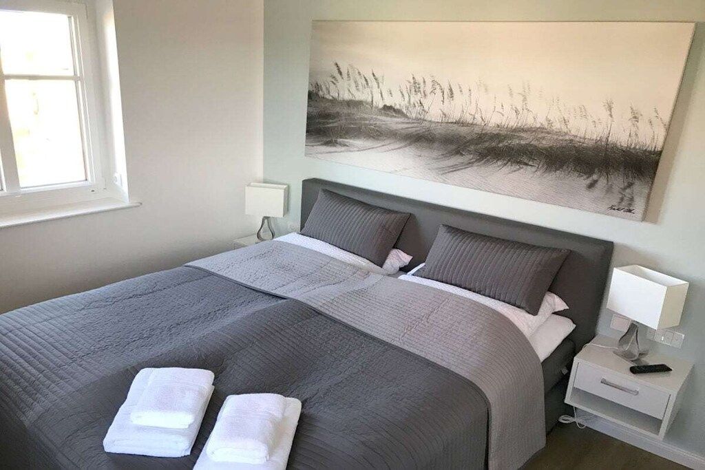 Ein Hotelzimmer mit einem großen Bett, zwei Kissen, einem Nachttisch mit Lampe und einem Bild an der Wand.