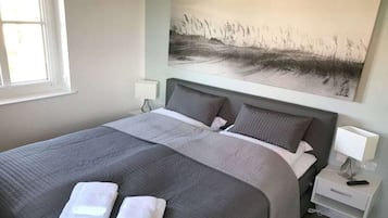 Ein Hotelzimmer mit einem großen Bett, zwei Kissen, einem Nachttisch mit Lampe und einem Bild an der Wand.