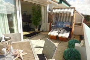Ein Balkon mit einer Couch, einem Esstisch und einem Blumentopf.