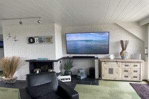 A modern living room with a fireplace, a flat-screen TV, and a comfortable seating area. - Holiday apartment in Büsum with swimming pool (Büsum)