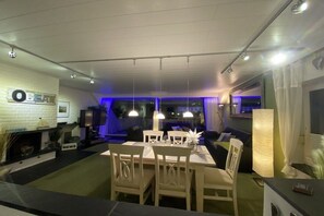 Ein moderner Essbereich mit Tisch, Stühlen, einem Kamin und einem Fernseher.