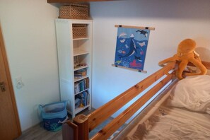 Ein Kinderzimmer mit Etagenbett, Bücherregal, einem Poster und einem Stofftier.