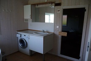 Pieni kylpyhuone, jossa on pesukone, pesuallas ja peili.