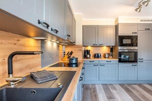 A modern kitchen with grey cabinets, a black sink, and a wooden countertop. - Holiday apartment with 2 bedrooms (Oevenum)