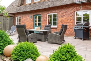 An outdoor patio with wicker furniture, a grill, and a brick house. - Holiday apartment with 2 bedrooms (Oevenum)