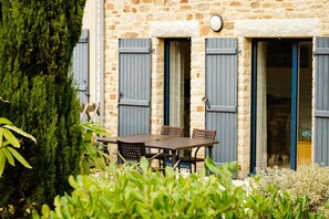 A stone building with a wooden table and chairs outside, surrounded by greenery. - Breton Alcove Stay for Six (Cancale)