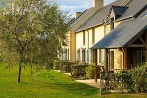 A building with a sloped roof, a garden with a tree, and a pathway leading to the entrance. - Breton Alcove Stay for Six (Cancale)