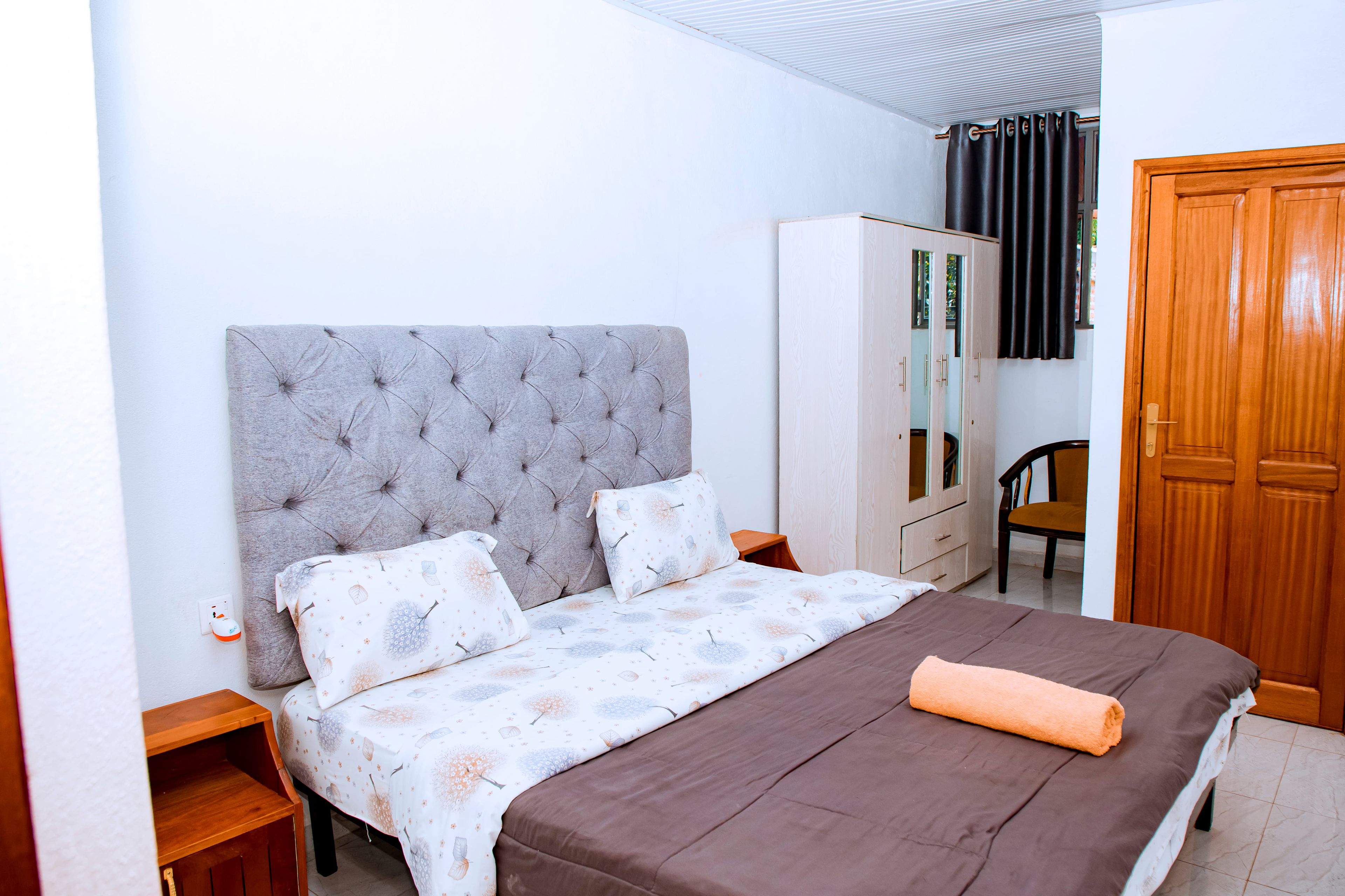 Un dormitorio con cama, armario, silla y espejo.