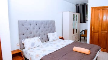 Un dormitorio con cama, armario, silla y espejo.