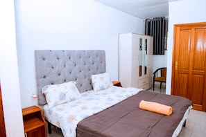 Un dormitorio con cama, armario, silla y espejo.