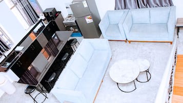Ein modernes Wohnzimmer mit einer Couch, einem Esstisch und einer Küchenzeile mit Herd.