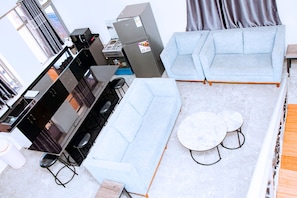 Una sala de estar moderna con sofá, una mesa de comedor y una zona de cocina con estufa.