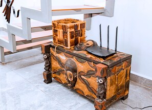 Een houten tafel met uitgehouwen dierenfiguren en een modern elektronisch apparaat erop.