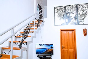 A staircase with a unique design, a framed artwork on the wall, a television, and a wooden door.