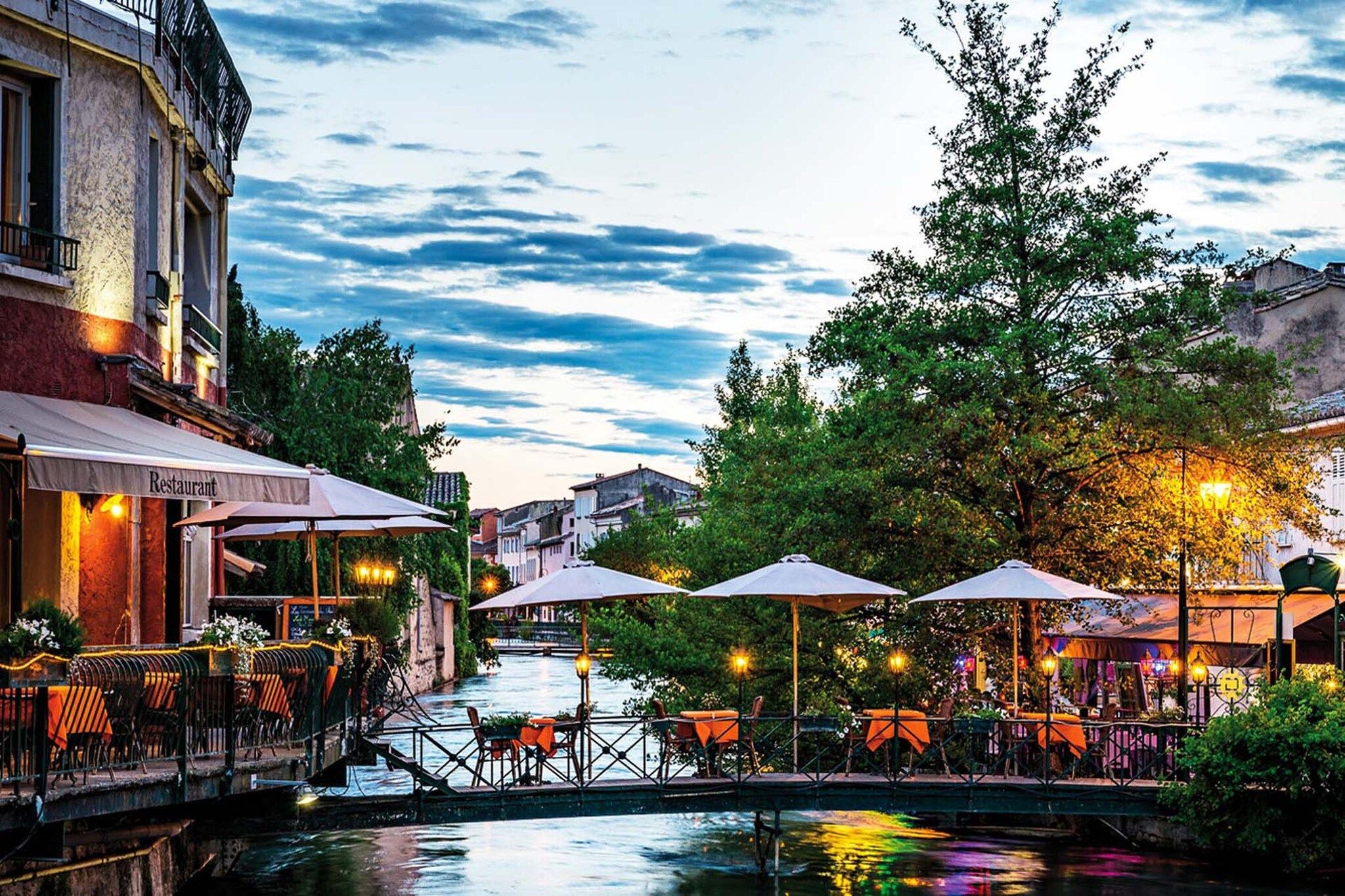 Un restaurante junto al río con terraza y vistas al agua.