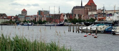 Un port où sont amarrés des bateaux, un bâtiment remarquable avec un toit rouge et un mélange d’architecture traditionnelle et moderne.
